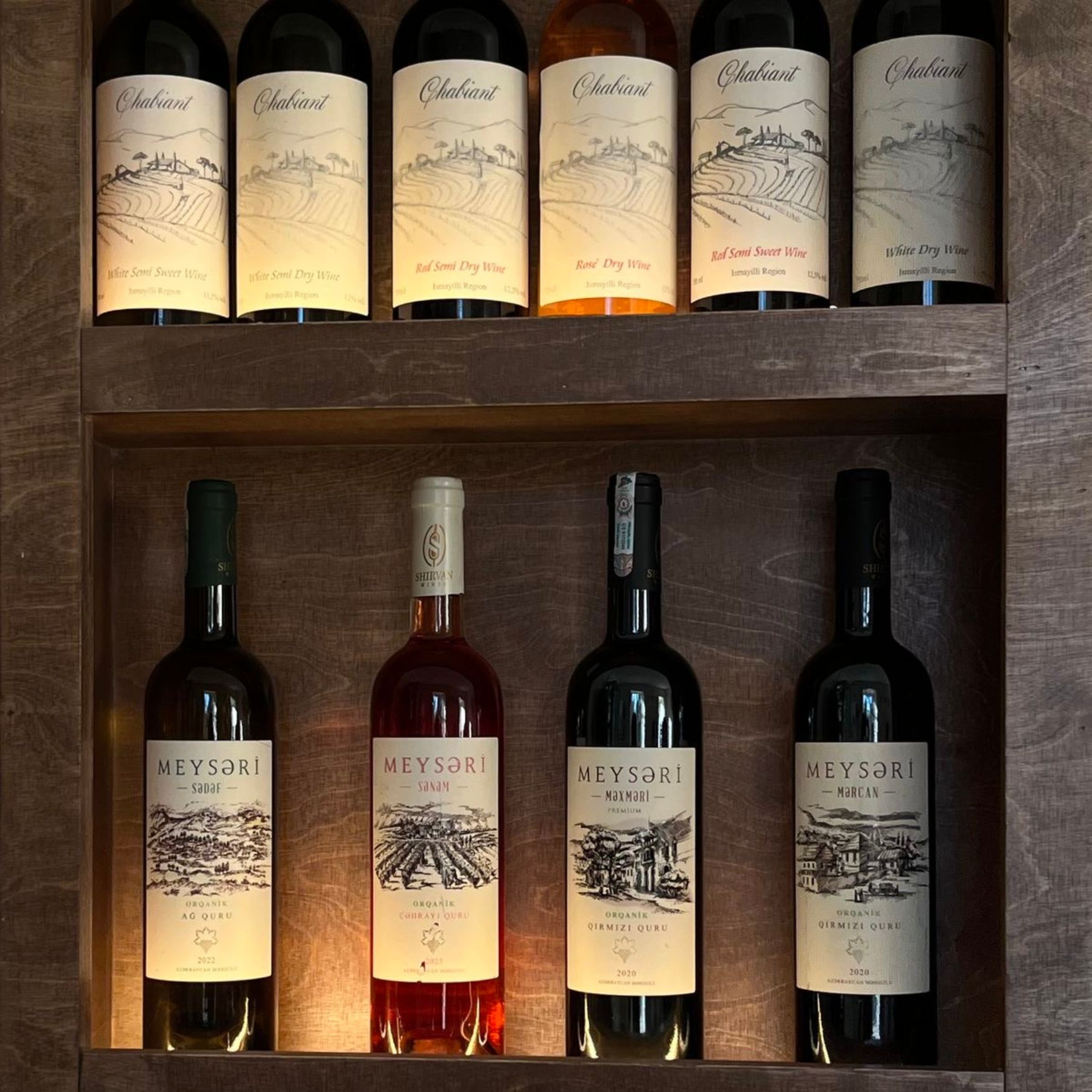 Weinflaschen in einem beleuchteten Holzregal in der Weinlaube