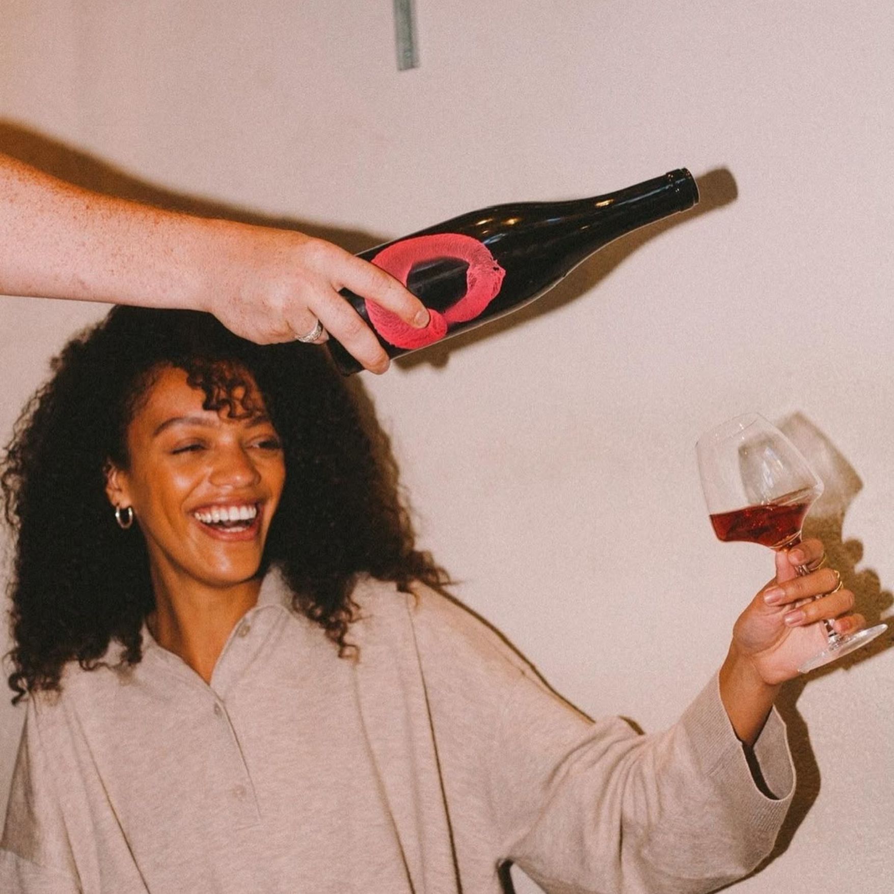 Frau lacht und hält ein Glas Rotwein hoch
